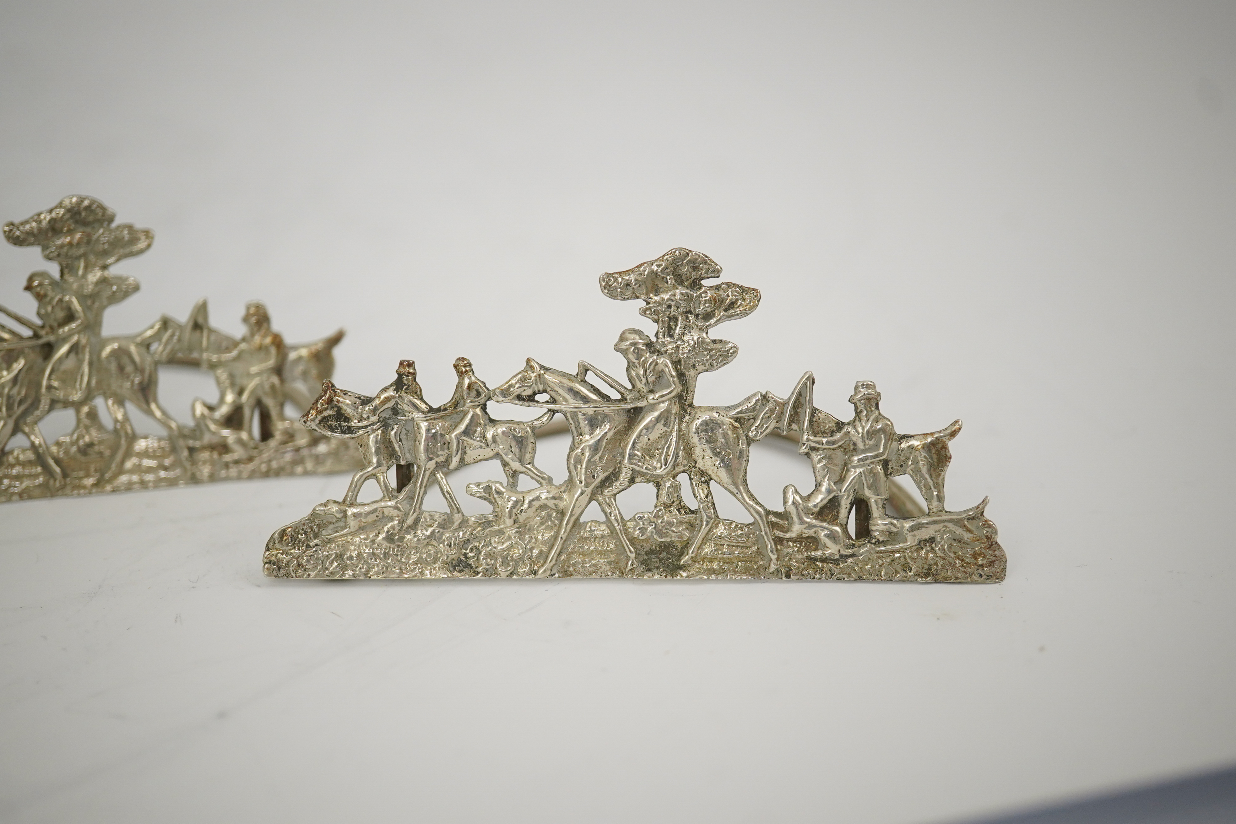 A set of four Edwardian pierced silver 'hunting scene' menu holders, by Stuart Clifford